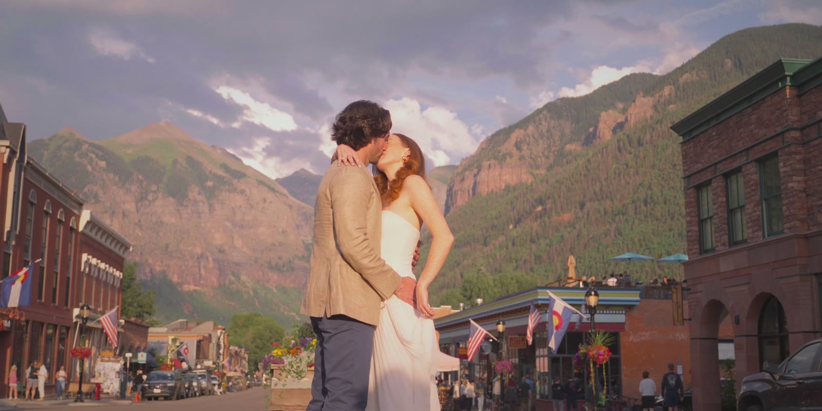 Kate and Adam kissing on Colorado Avenue in Telluride, mountains behind