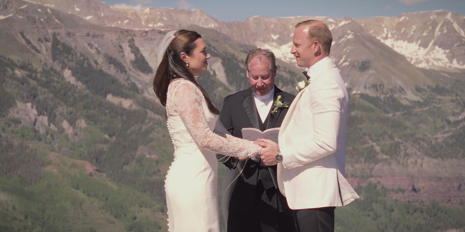 Sadie and Gavin exchanging vows above the valley, snow on the peaks